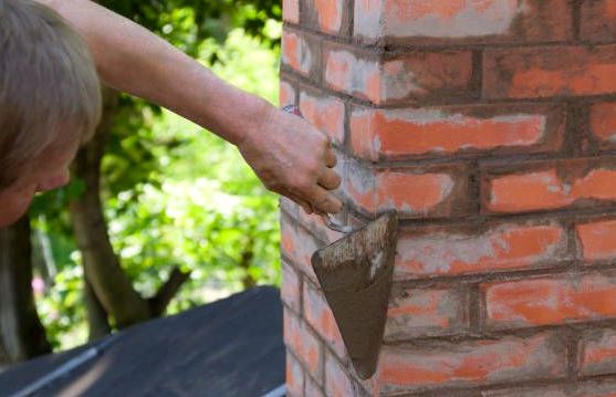 Pointing trowel pressing fresh mortar into pre-war brickwork